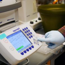 a gloved hand operates an operation panel.
