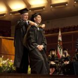 Kearney places a graduation hood on a student on stage