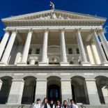 group stands in front of a government building.