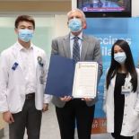 Guglielmo holds the official proclamation of Pharmacist Day in San Francisco while surrounded by PharmD students.