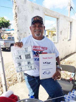 Puerto Rico resident holds a water filter and a sign saying Thank You UCSF.
