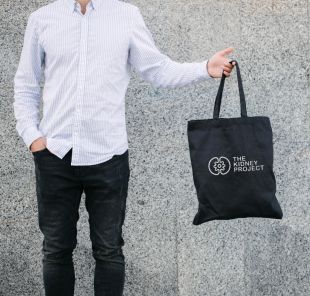 Person holding tote bag with The Kidney Project logo