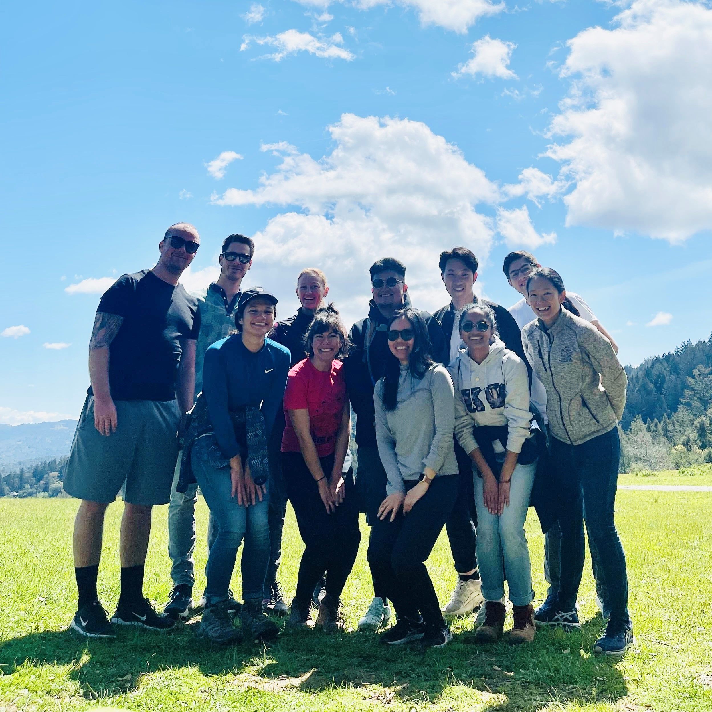Lab members in a green field in the mountains on a nice day