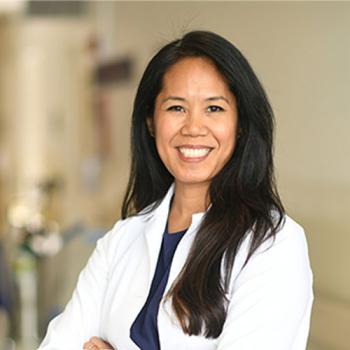 Jennifer Cocohoba in a white coat standing in a hospital hallway