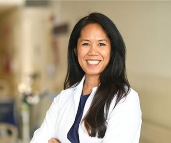 Jennifer Cocohoba in a white coat standing in a hospital hallway