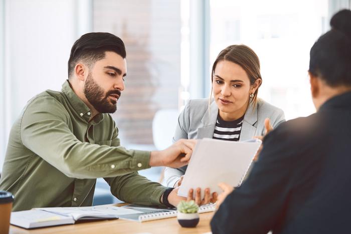 man points to paper while woman looks on