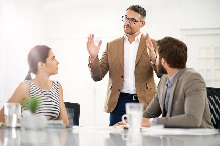 man presents idea to two colleagues who are listening in a conference room
