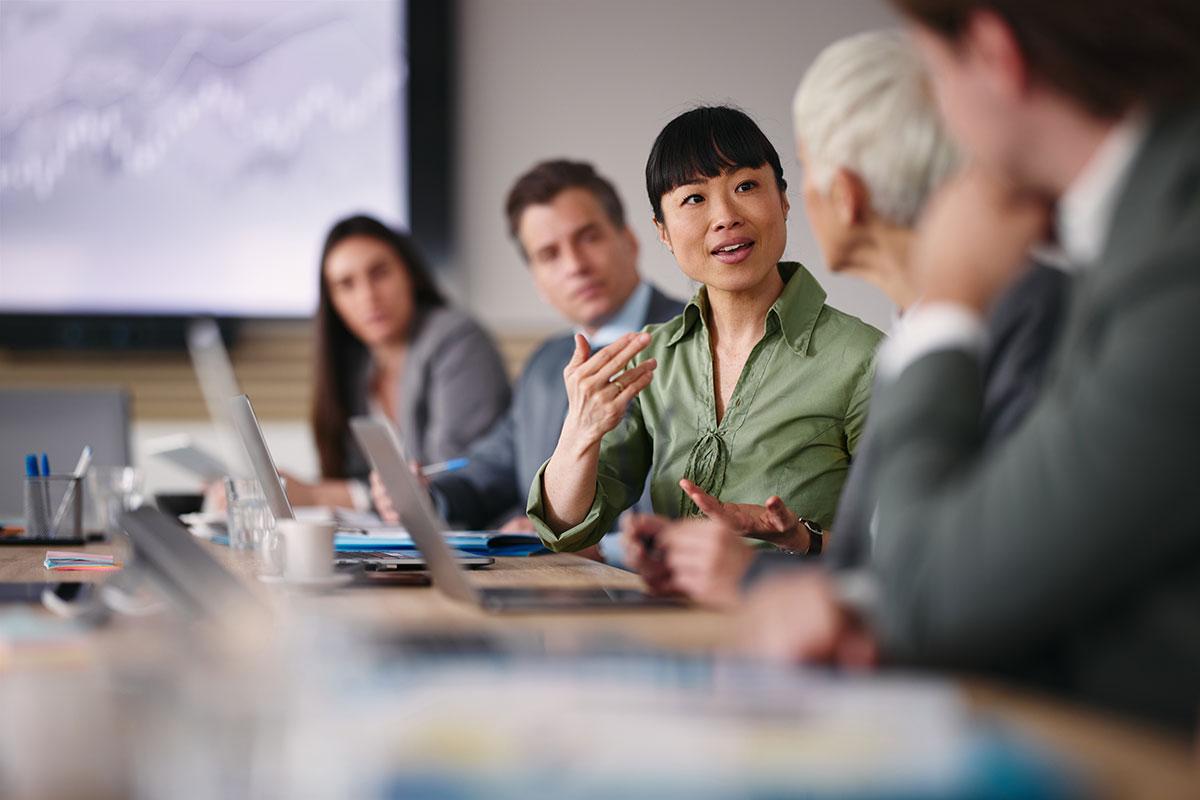 woman speaking in conference room with colleagues listening